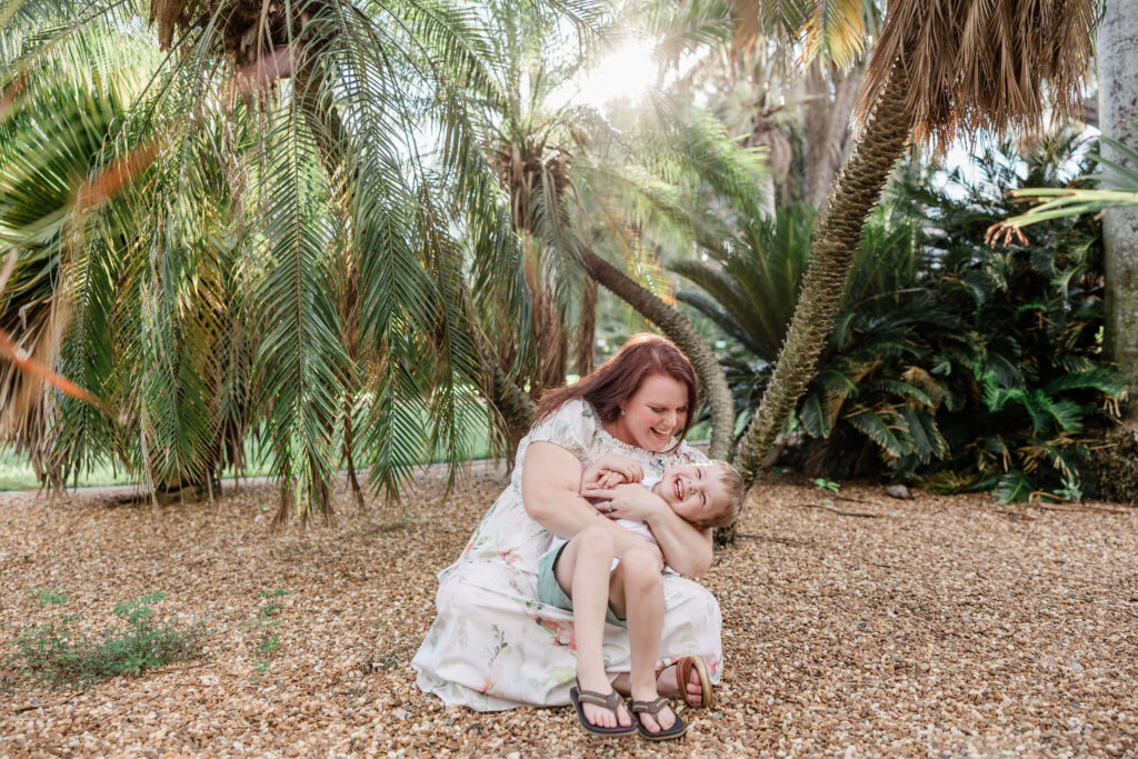 mother and child laugh together during photo shoot in St. Pete, FL at the gizella kopsick palm arboretum